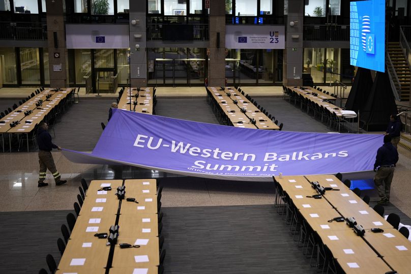 Workers begin installing a banner in the press room for an EU-Western Balkans summit at the European Council building in Brussels, December 2023