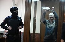 L'attivista russo per i diritti umani Oleg Orlov mostra le manette in tribunale