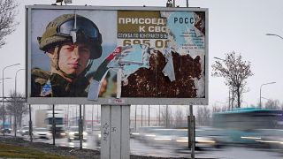 Cars drive past an advertising billboard in St. Petersburg promoting contract military service in the Russian army.
