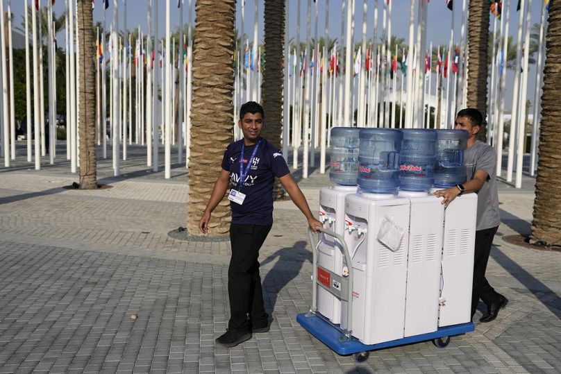 Workers move water jugs as the COP28 U.N. Climate Summit comes to an end in Dubai, December 2023