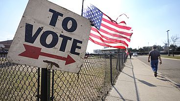 A sign pointing people in the direction of a voting both in the US. 