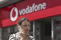 A woman talking on her mobile walks past a Vodafone store in London. June 14, 2023. 