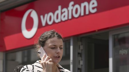 A woman talking on her mobile walks past a Vodafone store in London. June 14, 2023. 