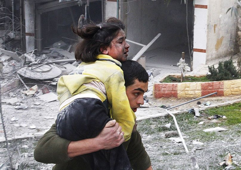 Syrian man carries his sister who was wounded in a government airstrike hit the neighbourhood of Ansari, in Aleppo, February 2013