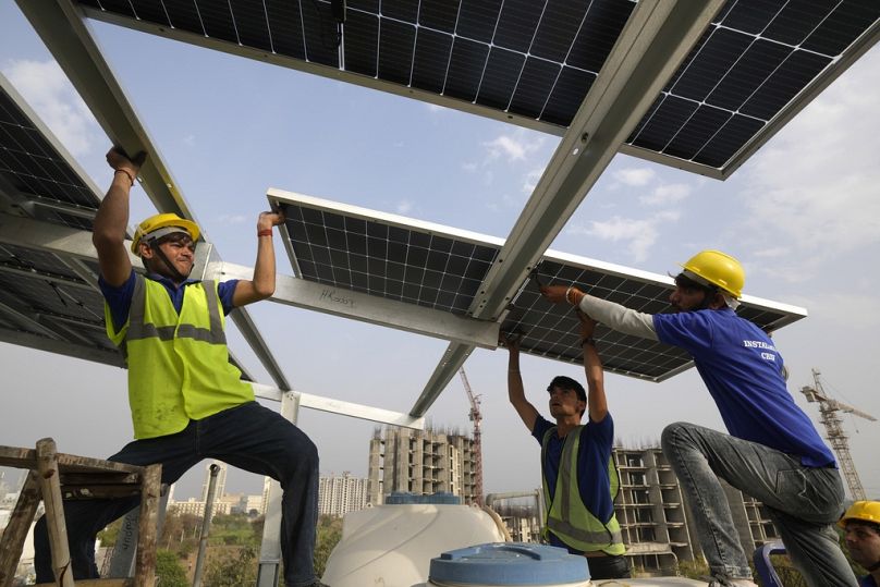 Workers put up a panel on the rooftop of a residence in Gurugram on the outskirts of New Delhi, February 2024