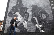 Loyalist activist Jamie Bryson walks past a Ulster Volunteer Force mural in east Belfast, Northern Ireland, Tuesday, Oct. 15, 2019. 