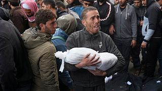 فلسطيني يحمل جثة طفل قتل في القصف الإسرائيلي - مستشفى الأقصى في دير البلح، الجمعة، 23 فبراير، 2024