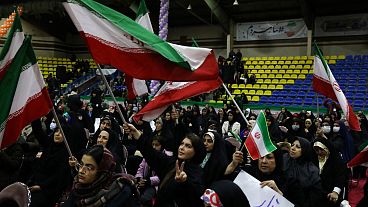 Iranian women wave their country's flags during an election campaign rally ahead of the March 1, parliamentary and Assembly of Experts elections, in Tehran on Feb. 27.