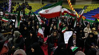 نساء إيرانيات يلوحن بأعلام بلادهن خلال تجمع انتخابي