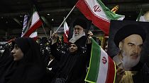 Mujeres iraníes ondean banderas de su país con carteles del líder supremo, el ayatolá Ali Jamenei, y del difunto fundador revolucionario, el ayatolá Jomeini