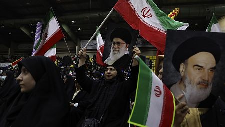 Mujeres iraníes ondean banderas de su país con carteles del líder supremo, el ayatolá Ali Jamenei, y del difunto fundador revolucionario, el ayatolá Jomeini