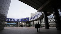 Persone camminano sotto uno striscione che pubblicizza le elezioni europee fuori dal Parlamento europeo a Bruxelles, mercoledì 24 gennaio 2024