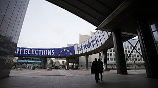 Persone camminano sotto uno striscione che pubblicizza le elezioni europee fuori dal Parlamento europeo a Bruxelles, mercoledì 24 gennaio 2024