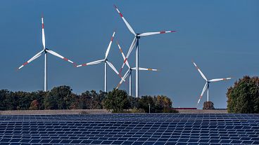 Wind turbines turn behind a solar farm in Rapshagen, Germany.