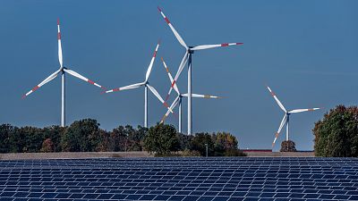 Des éoliennes tournent derrière un parc solaire à Rapshagen, en Allemagne.
