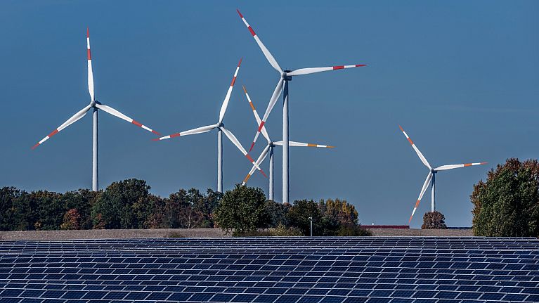 Wind turbines turn behind a solar farm in Rapshagen, Germany.
