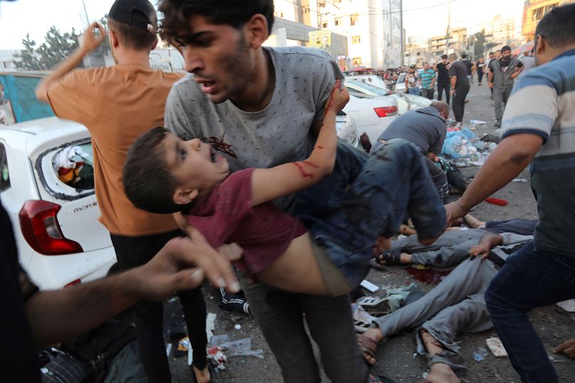 شاب فلسطيني يحمل طفلا أصيب جراء القصف الإسرائيلي في محيط مجمع الشفاء الطبي03/11/2023
