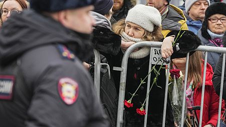A Police officer guards as people gather near the Church of the Icon of the Mother of God Soothe My Sorrows, in Moscow