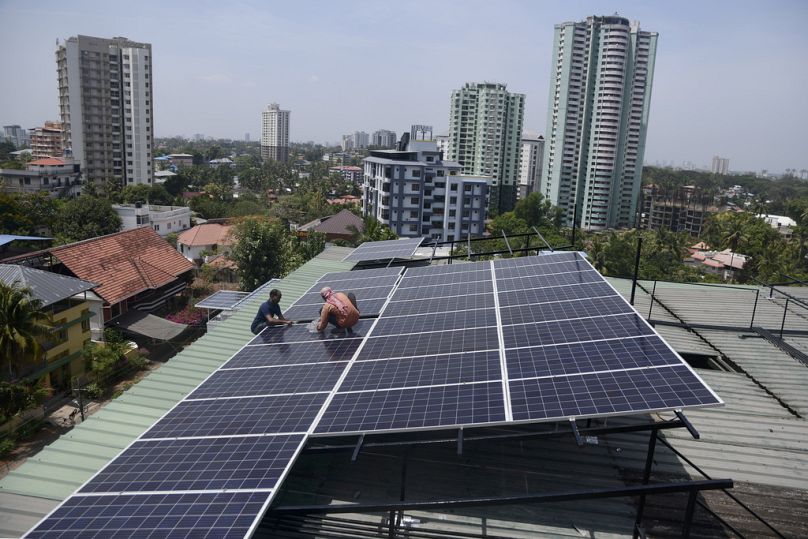 Alcuni operai installano pannelli solari sul tetto di un appartamento residenziale a Kochi, nello stato meridionale del Kerala, in India.