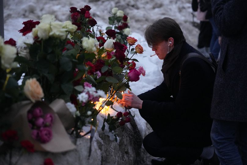 People lay flowers and candles paying the last respect to Alexei Navalny, in a street not far from the Borisovskoye Cemetery in Moscow, Russia, Friday, March 1, 2024.