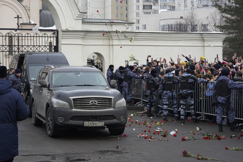 People throw flowers as a van with the coffin of Russian opposition leader Alexei Navalny leaves the Church of the Icon of the Mother of God Soothe My Sorrows, in Moscow.
