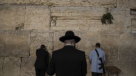 Yahudilerin ibadet ettiği en kutsal yer olan Batı Duvarı'nda dua eden  aşırı Ortodoks Yahudi erkekler ve İsrail güvenlik güçlerine bağlı bir asker