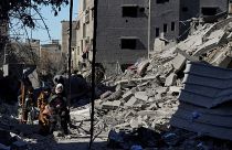 عائلة فلسطينية تمشي وسط ركام المباني المدمرة جراء القصف الإسرائيلي في مخيم النصيرات وسط غزة. 2024/02/29