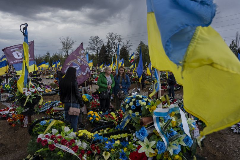 Friends and relatives visit the grave of a Ukrainian serviceman at the Kryvyi Rih cemetery in eastern Ukraine, Sunday, April 23, 2023.