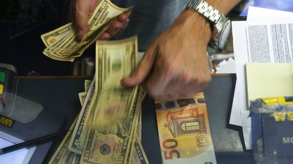 Un cassiere cambia una banconota da 50 euro in dollari USA presso uno sportello di cambio a Roma, Italia
