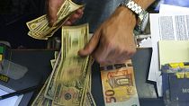 Ein Kassierer wechselt an einem Geldwechselschalter in Rom, Italien, eine 50-Euro-Banknote in US-Dollar.