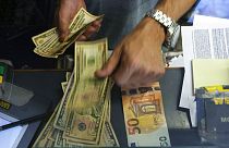 Uma caixa troca uma nota de 50 euros por dólares americanos num balcão de câmbio em Roma, Itália