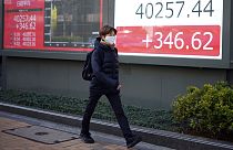 Una persona camina delante de una pizarra electrónica que muestra el índice Nikkei 225 de Japón en una empresa de valores el lunes 4 de marzo de 2024, en Tokio.