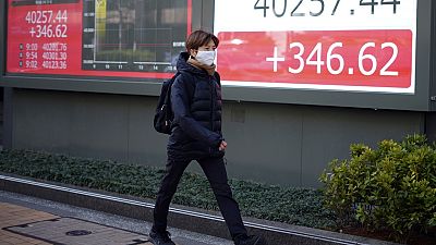 Una persona camina delante de una pizarra electrónica que muestra el índice Nikkei 225 de Japón en una empresa de valores el lunes 4 de marzo de 2024, en Tokio.