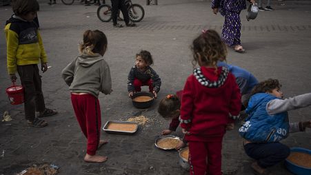 أطفال فلسطينيون يحصلون على طعام في رفح بقطاع غزة، الجمعة،