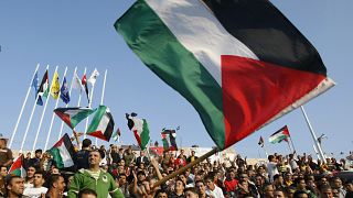 مشجعو كرة القدم الفلسطينية يلوحون بالأعلام الفلسطينية قبل مباراة كرة قدم