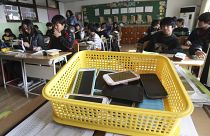 Smartphones recolhidos dos alunos são colocados num cesto de plástico durante uma aula na escola primária de Chilbo em Suwon, Coreia do Sul.