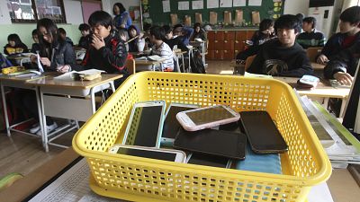 Smartphones recolhidos dos alunos são colocados num cesto de plástico durante uma aula na escola primária de Chilbo em Suwon, Coreia do Sul.