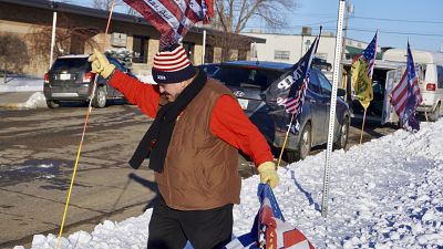 Donald Trump supporter Charles Tuttle, of Minot, sets out a row of Trump flags outside Minot Municipal Auditorium, where voting in the GOP caucus took place 4 March 2024