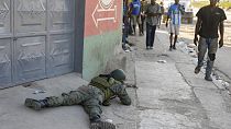 Varios peatones pasan junto a un soldado que vigila la zona del aeropuerto internacional de Puerto Príncipe, Haití, el lunes 4 de marzo de 2024.
