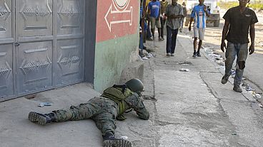 Pedestrians was past a soldier guarding the area of the international airport in Port-au-Prince, Haiti, Monday, March 4, 2024. 