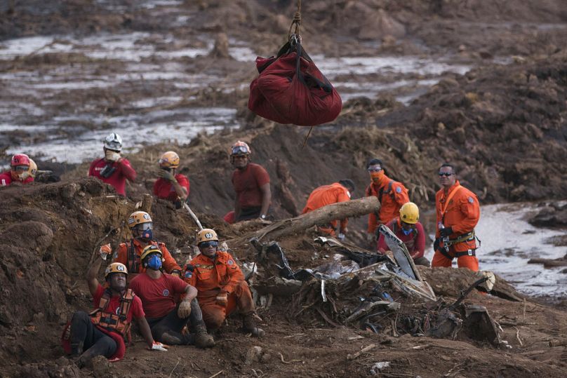 Firefighters watch the body of a person they pulled from the mud, as it is lifted up and taken away by a helicopter days after a dam collapse in Brumadinho, January 2019