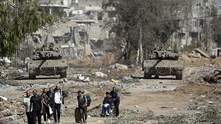 مجموعة من النازحين الفلسطينيين أمام الدبابات الإسرائيلية في قطاع غزة
