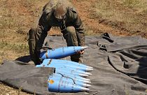 Солдат НАТО поднимает артилллейский снаряды