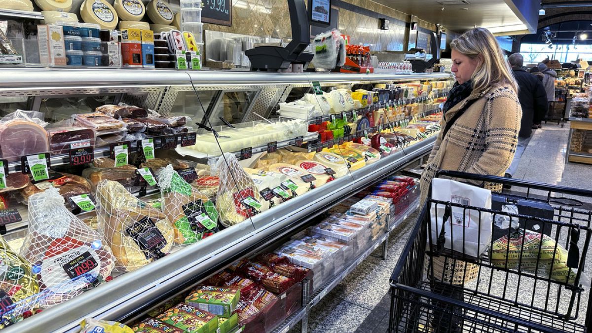 A woman checks prices as she shops at a grocery store in Wheeling, Ill., Friday, Jan. 19, 2024. 