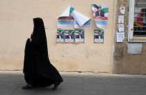 A woman walks past electoral posters of candidates for the March 1, parliamentary election, in downtown Tehran, Iran, Thursday, Feb. 22, 2024. 
