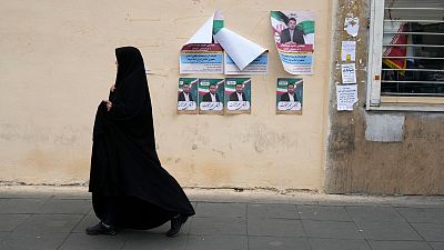 A woman walks past electoral posters of candidates for the March 1, parliamentary election, in downtown Tehran, Iran, Thursday, Feb. 22, 2024. 