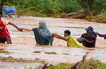 Moradores atravessam uma estrada danificada pelas chuvas do El Niño em Tula, no condado de Tana River, no Quénia, em 25 de novembro de 2023. 
