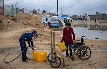 Palestinians displaced by the Israeli air and ground offensive on the Gaza Strip gather water in a makeshift tent camp in Rafah on the border with Egypt, 27 January 2024.