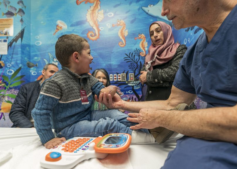 Dört yaşındaki Omar Abu Kuwaik, ortopedi cerrahı Dr. Scott Kozin Shriners Çocuk Hastanesi'nde kolunu incelerken ağlıyor