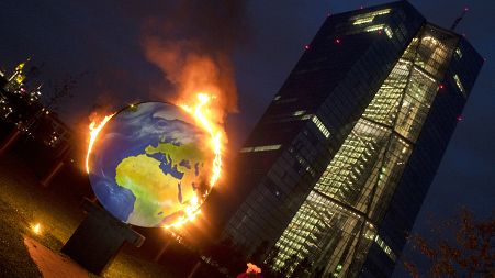 A makeshift globe burns in front of the ECB in Frankfurt, Germany, as activists protest against the bank's climate policy, Oct. 21, 2020. 